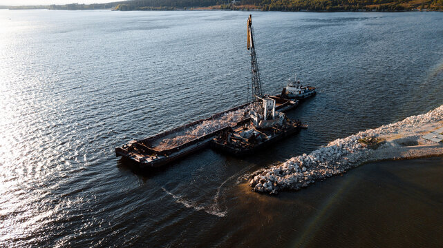 Top-view of a floating crane unloading barge with stones