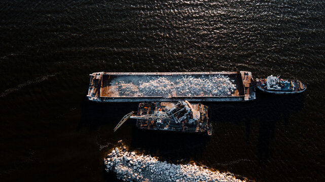Top-view of a floating crane unloading barge with stones