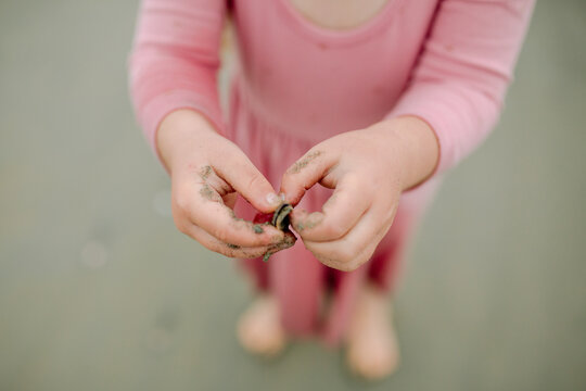 Young girl in pink dress holding seashells