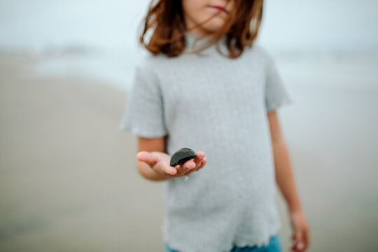 Young girl in blue shirt holding seashell