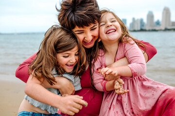 Pregnant mom tickling daughters at beach
