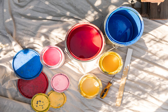 Colorful Paint Cans Sitting On A Tarp Outdoors