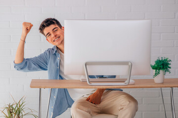 satisfied male teenage student at desk with computer