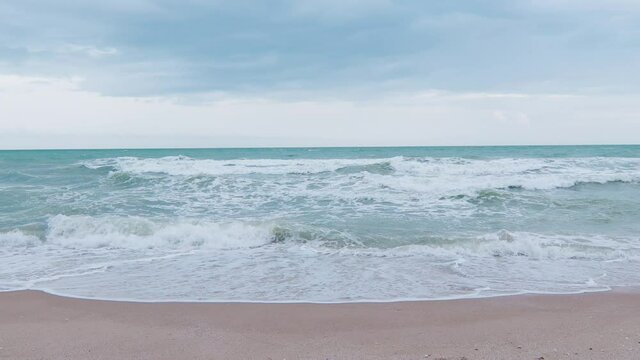 Front view with low angle 4K of sea beach seeing strong and turbulent waves with water splash, clear sky, clouds, horizon which is beautiful scenic of tropical ocean coast for travel vacation.