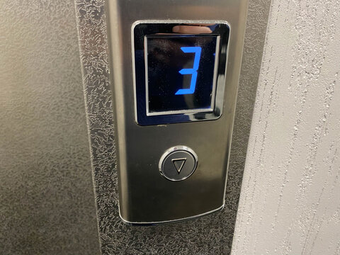 Metallic shiny chrome plated modern elevator call button with floor designation display in modern building