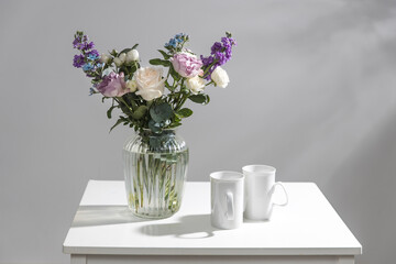 Bouquet of hackelia velutina, purple and white roses, small tea roses, matthiola incana and blue iris in glass vase