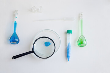 Set of school supplies for biology or chemistry lesson on light background: petry dish with Cu salt, magnifier, tweezers, plastic tubes, pipette. Concept: back to school. Flatlay, top view. - Powered by Adobe