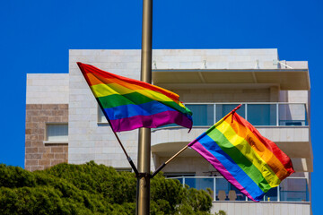 Rainbow flags hanging on a pole and waving on the air with blue sky background. LGBTQ community....