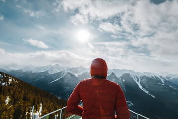 Fototapeta na wymiar A man with a red jacket looking at the Canadian Rockie mountains in Banff, Canada