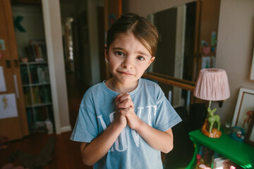 portrait of a girl making a sad face with her hands clasped