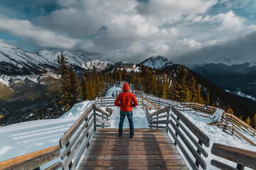 A man with a red jacket looking at the Canadian Rockie mountains in Banff, Canada - obrazy, fototapety, plakaty