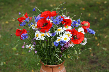 Bouquet of cornflowers, daisies and poppies to decorate the solstice festival in clay vase