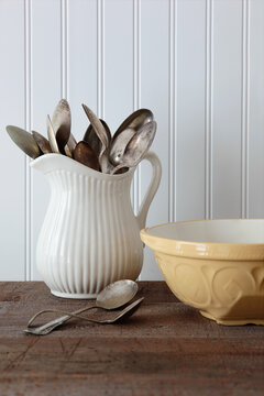 Vintage spoons in jug on kitchen table 