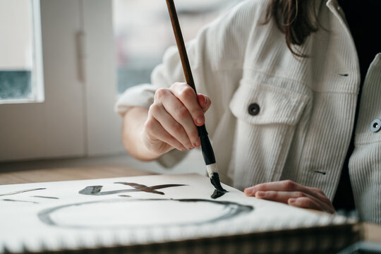 Young woman writing japanese kanji characters with a brush and ink