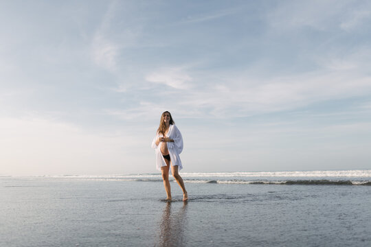 pregnant  woman walks on the beach