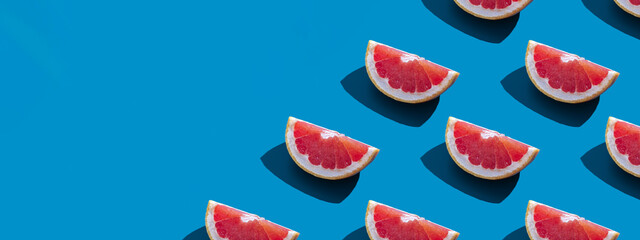 Seamless pattern of orange grapefruit with shadow on a blue background with copy space. Banner. Summer vacation minimal trendy concept. Healthy eating habits.