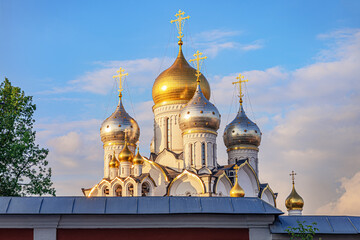 Fototapeta na wymiar domes of an old russian orthodox church against a bright sky behind the monastery wall, Conception stavropegic convent, Moscow, Russia
