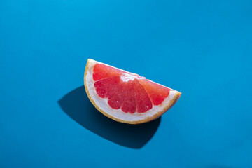 Creative concept. Sliced ​​juicy orange grapefruit with shadow isolated on blue background. Tropical fruit minimal composition.