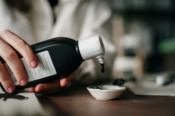 Close up of woman pouring black ink on plate for sumi e painting