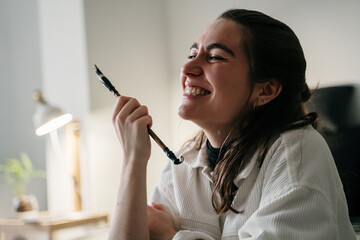 Portrait of happy Young woman writing japanese kanji characters with a brush and ink