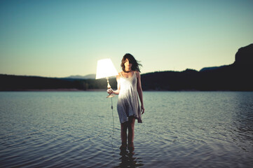 Girl standing in the lake holding a lamp