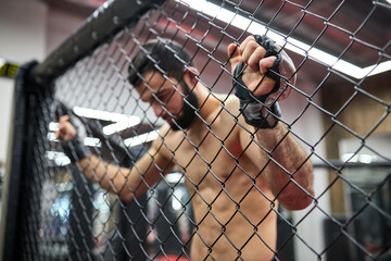 Mixed Martial Arts. mma, strong fighter in the octagon, resting in ring after fight, need some rest, shirtless muscular male is looking down. focus on hands on gloves