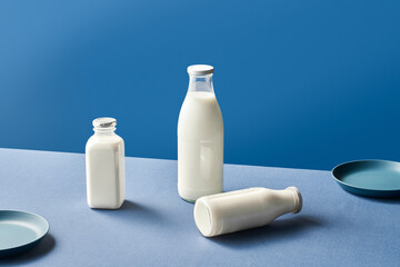 Bottles of milk and plates on blue table