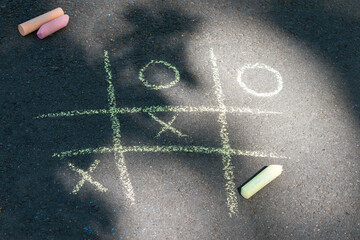Tic-tac-toe chalk game on asphalt, drawing on the sidewalk.