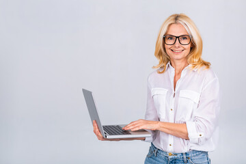 Image of cheerful mature business woman standing isolated over white background using laptop...