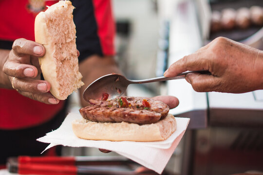 Adding criolla sauce to a choripan in Buenos Aires