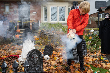 Boy Setting up Skull Scary Halloween Decorations in Front Yard for Trick-Or-Treat Fright