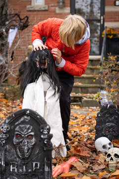 Boy Setting up Scary Halloween Decorations in Front Yard for Trick-Or-Treat Fright