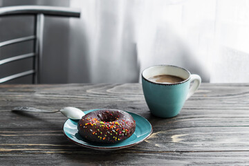 Morning coffee. Breakfast in a cafe with a cup of coffee and a donut on a wooden table. Copy space.