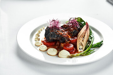 Veal cheeks with vegetables in demi-glace sauce, top view, close-up, white plate - obrazy, fototapety, plakaty