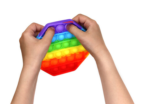 Anonymous child with colorful poppit game. Close up bunner shot of kid hands playing with colorful pop It fidget toy.