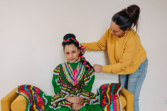 Mother helping daughter to put accessories on for a Mexican performance