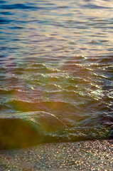 pebble stones on the sea beach, the rolling waves of the sea with foam