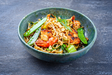 Modern style traditional Thai phak kung curry with barbecue king prawns and noodles as close-up in Nordic design bowl with copy space