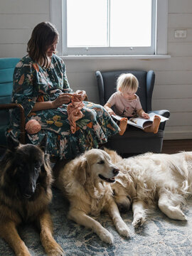 Woman knitting alongside her daughter and dogs