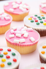 Colorful cupcakes on a pink background.