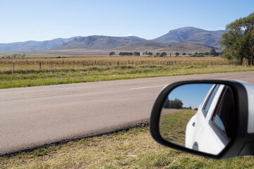 Travelers: mirror of a car and in front a beautiful mountain landscape