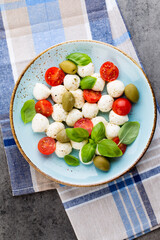 Delicious caprese salad with ripe cherry tomatoes and mini mozzarella cheese balls with fresh basil leaves.