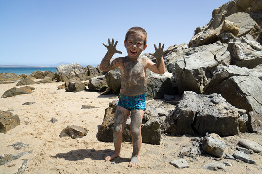 Child with the body slathered in mud on a beach