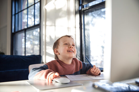 Little boy smiling while using desktop computer