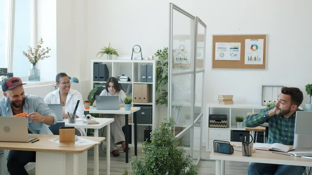 Carefree businesspeople enjoying toy guns fight in office having fun together smiling relaxing during work break. Youth entertainment cnd lifestyle concept.