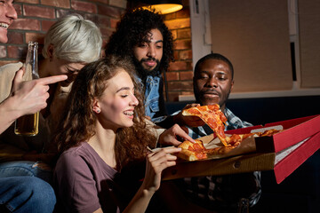 men and women eating pizza and watching tv.Home party.Fast food concept. Americans spending free...