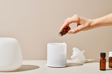 Crop person preparing aromatic liquid for diffuser