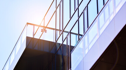 Reflection of modern commercial building on glass with sunlight. Geometric structure glass windows. 