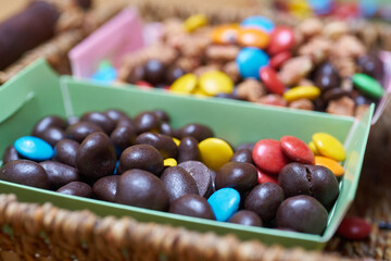 Christmas sweets in a decorated basket: chocolate peanuts, colored candies and sugary peanuts