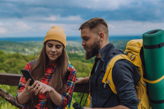 Young couple of hikers using smartphone while trying to find out their location